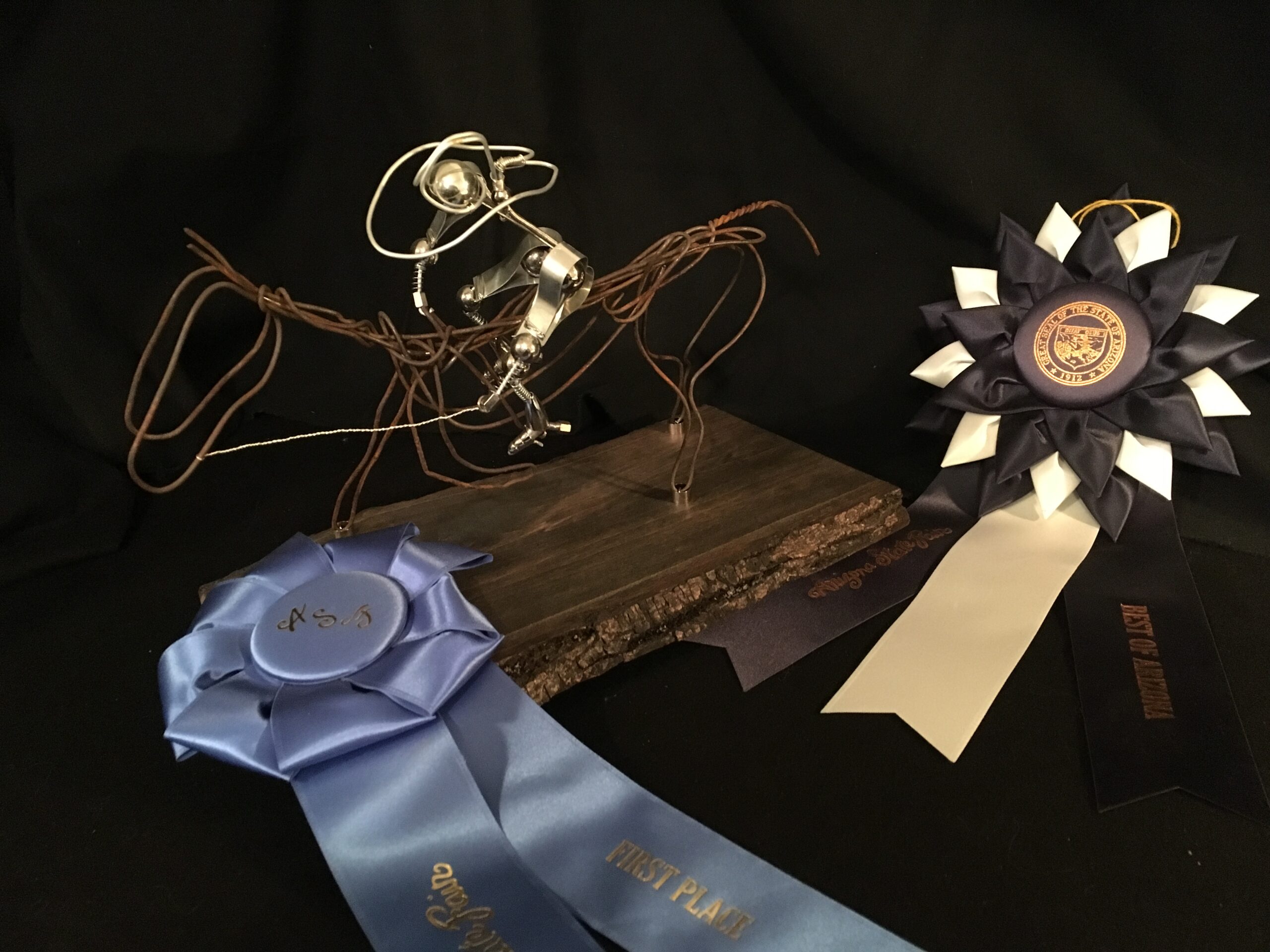 OneWire BR004 is a Large sized, antique bailing wire OneWire sculpture that features a dual head, bailing wire tail and a stained wooden base. Rider is made of stainless steel and aluminum. OneWire Br004 took “Best of Show”, 2019 Maricopa County Fair (AZ), (Amature, sculpture, metal art) BUL008 was constructed on April 20, 2019 in Fort Gibson, OK.