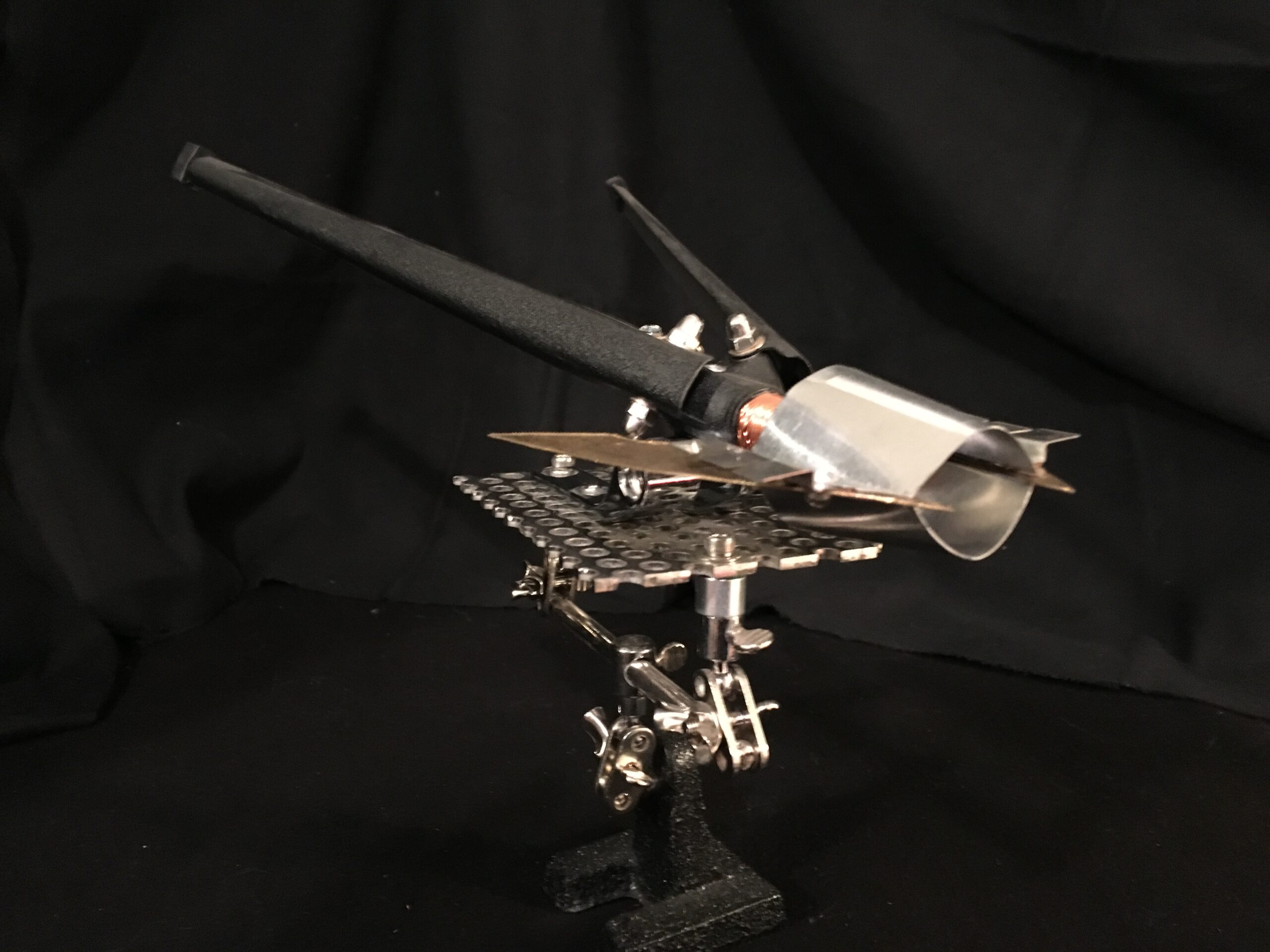 “Space Dart” is an assembly made up of a both found and fabricated parts, mainly surrounding a recovered, damaged table tripod. Space Dart features a handmade aluminum and brass forward hood/cowl. “Space Dart was completed in May, 2017 in Phoenix, AZ.